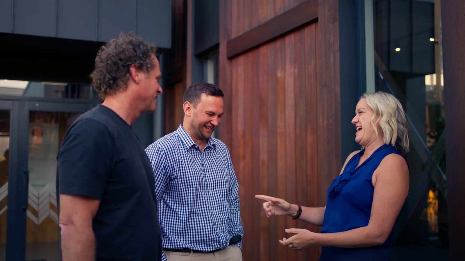 Mell laughing and pointing mid-conversation with Matt and a client
