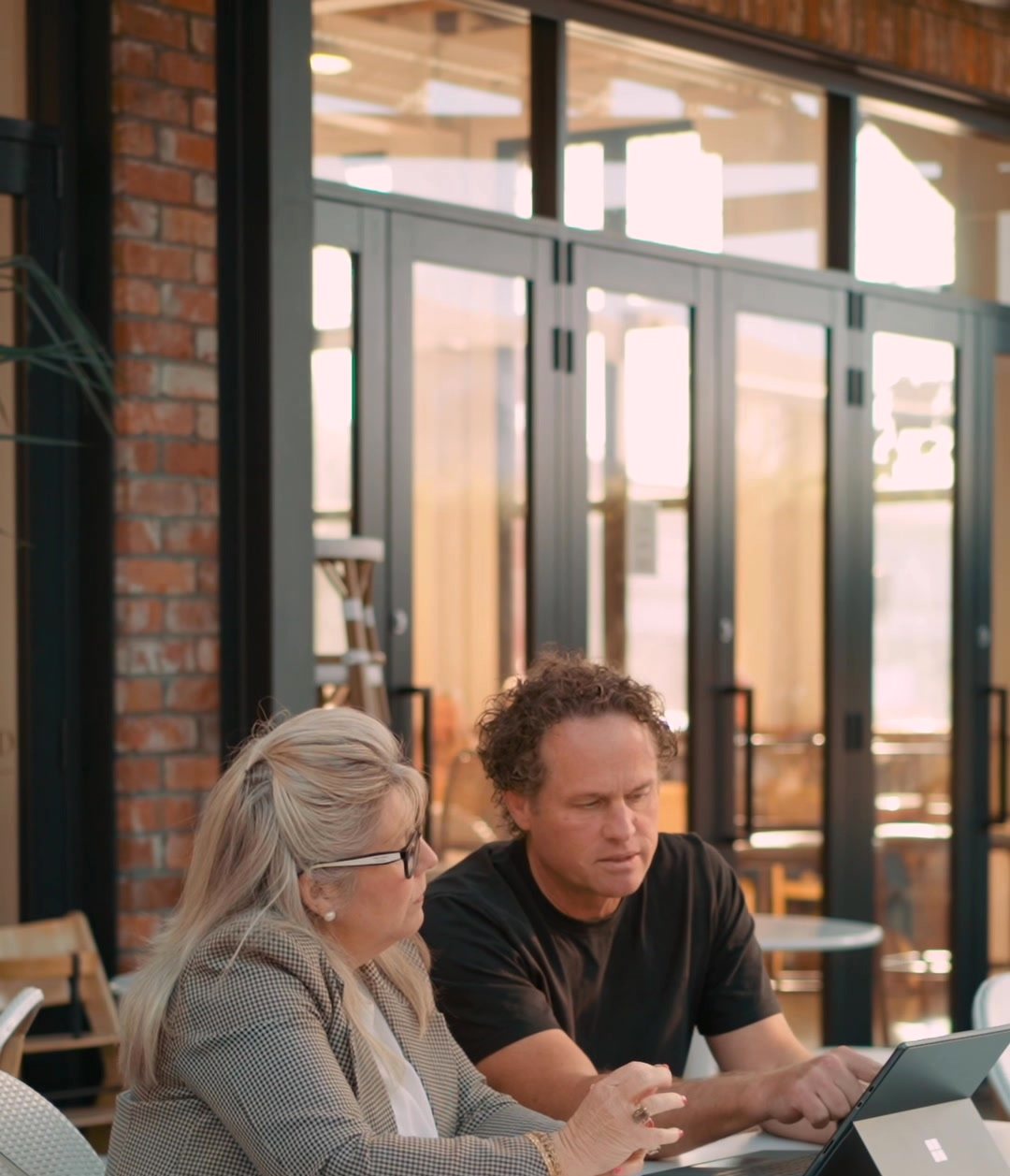 Matt and a client working side by side at a café table