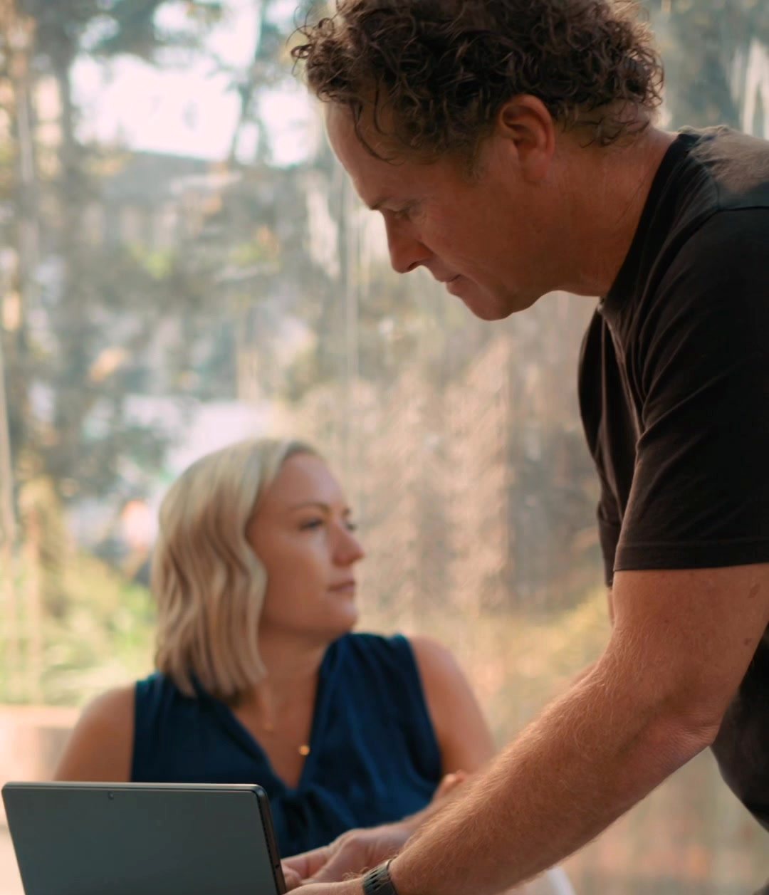 Matt leans in to show something on the laptop while Mell looks on